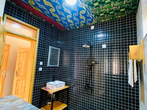 a bathroom with black tiled walls and a shower at Amara Kivu Resort in Île Bugarura