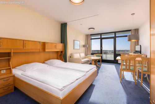 a hotel room with a bed and a dining room at IFA Yachthafen Fehmarn in Fehmarn