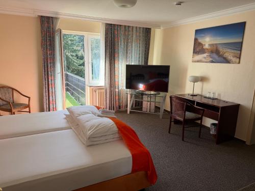 a bedroom with a bed and a desk and a television at Hotel Bremer Kreuz in Achim