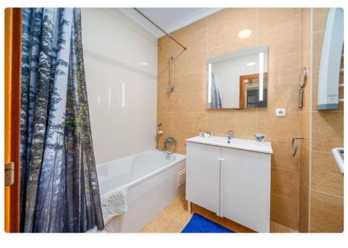 a bathroom with a tub and a sink and a mirror at Sunny apartamento in Portimão