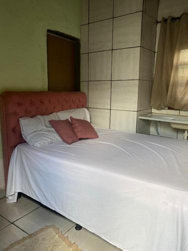 a large white bed with two pillows on it at Quarto para o Moto GP in Goiânia