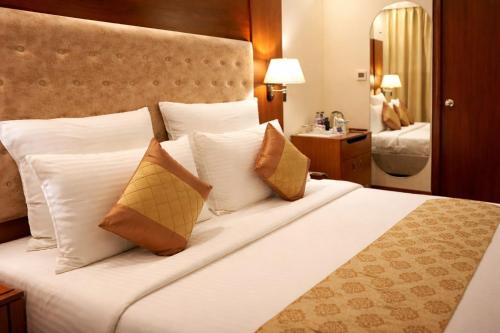 a bedroom with a large white bed with pillows at Hotel Saj Luciya in Trivandrum