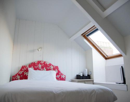 a bedroom with a bed with a red headboard and a window at The Tremont in Penzance