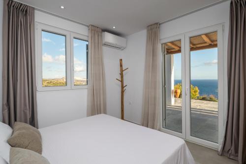 a bedroom with a bed and large windows at Endless Blue Anesea House in Provatas
