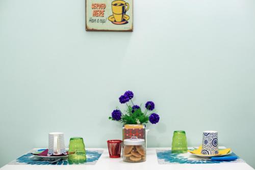 una mesa con platos y un jarrón con flores púrpuras en Viaggio a Napoli B&B, en Nápoles