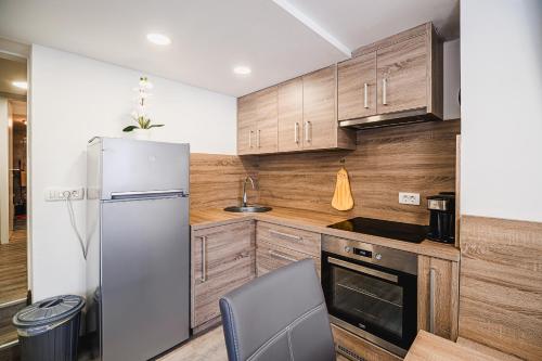 a kitchen with wooden cabinets and a refrigerator at Apartment Kamrca na Kopah in Šmartno pri Slovenj Gradcu