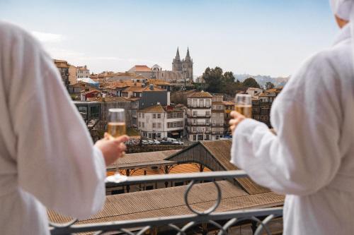 two people holding glasses of beer looking at a city at The Mila Porto in Porto