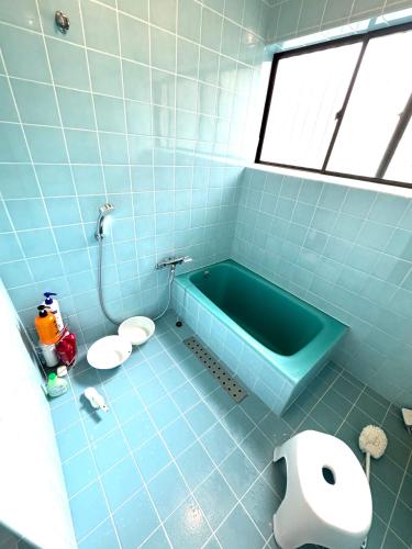 a blue tiled bathroom with a tub and a toilet at ゲストハウス虎のいえ in Sukumo