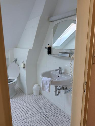 a bathroom with a sink and a toilet and a mirror at Hotel Bremer Kreuz in Achim