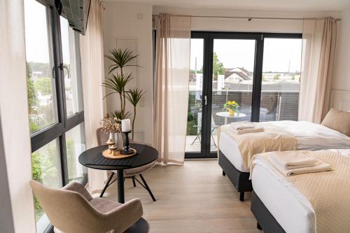 a bedroom with two beds and a table and a balcony at DOM Inn in Mörfelden-Walldorf