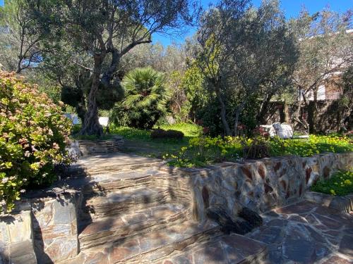 a stone path in a garden with flowers and trees at La Caseta de Cadaqués in Cadaqués