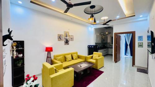 a living room with yellow furniture and a ceiling fan at Warm Nest in Dehradun