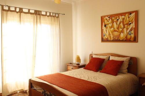 a bedroom with a bed with red pillows and a painting at Quinta Manuel Santo in Nazaré