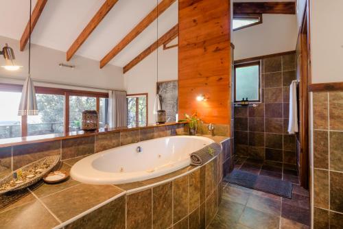 a large bathroom with a tub and a shower at Elephant Hide of Knysna Guest Lodge in Knysna