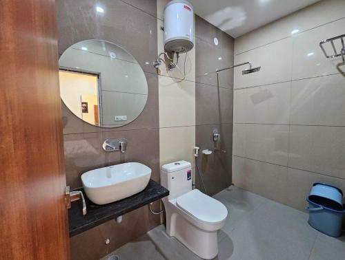a bathroom with a toilet and a sink and a mirror at Hotel Sunrise in Damoh