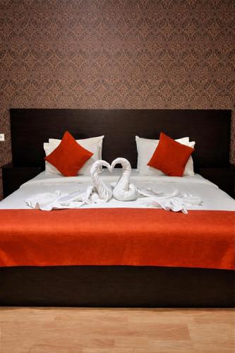 a bed with red pillows and two swansrendered to look like hearts at Hotel New Terrace in Tbilisi City
