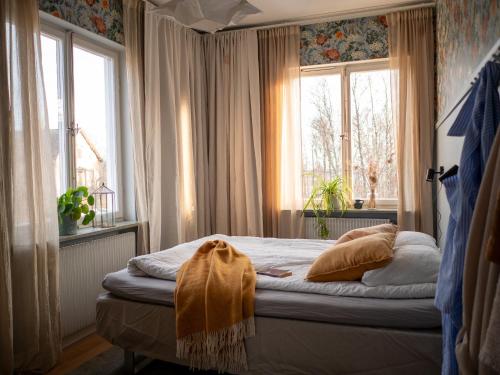 a small bedroom with a bed with two windows at Marinans Guesthouse in Nävekvarn
