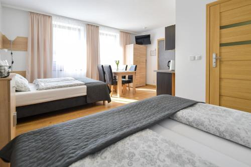 a hotel room with two beds and a kitchen and a table at Apartamenty Tilia Laskowa - Zator in Laskowa
