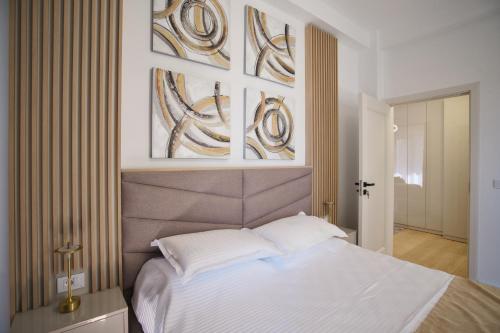 a bedroom with a white bed and paintings on the wall at ASTI Residence Aparthotel in Năvodari