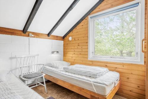 a bedroom with a bed and a chair and a window at 692-Thisted-Mose-Bollevej-6 in Thisted