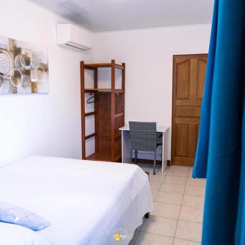 a bedroom with a bed and a table and a chair at Le Clos de Ébéniers in Saint-Laurent du Maroni