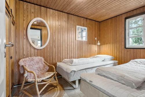a room with two beds and a chair and a mirror at 3392-Hvide-Sande-Fyrmarken-10 in Hvide Sande