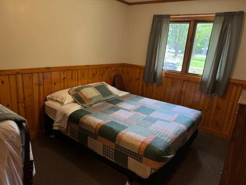 a bedroom with a bed with a quilt on it at Pine & Paddle in Saint Germain