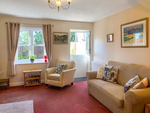a living room with a couch and a chair and windows at Middle Cottage in Thirsk