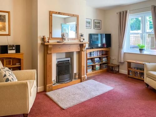 a living room with a fireplace and a mirror at Middle Cottage in Thirsk