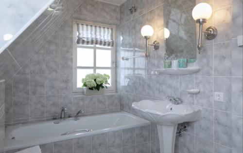 a bathroom with a tub and a sink and a mirror at Ferienhaus Weitblick in Morsum