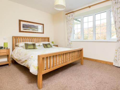 a bedroom with a wooden bed and a window at 3 Bed in Penrith oc-sz299 in Pooley Bridge