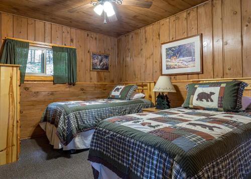 two beds in a room with wooden walls at Timbers - Bouchard Shores Resort in Minocqua