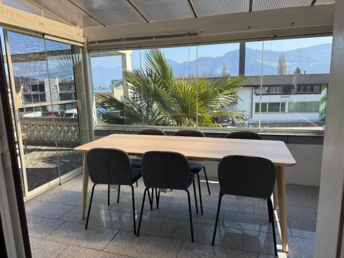 a table and chairs in a room with a large window at Lake View near Lucerne in Hergiswil