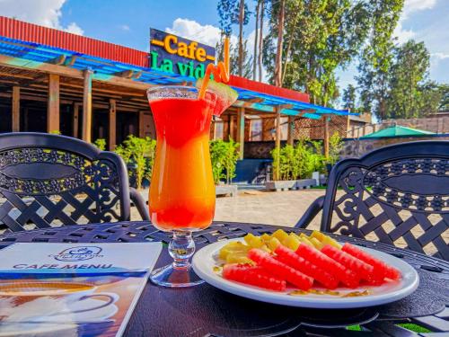 a table with a plate of fruit and a drink at Cafe La Vida in Mbarara