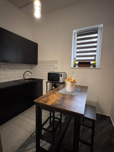 a kitchen with a wooden table and a microwave at Léda Vendégház in Vásárosnamény