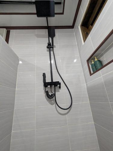 a shower on a white tiled floor in a bathroom at Jati Rinjani Tetebatu in Tetebatu