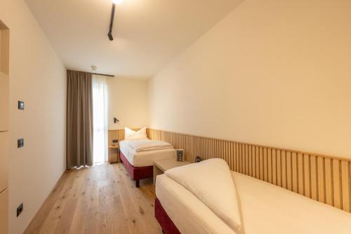a hotel room with two beds and a window at Etra Suites & Apartments in Riva del Garda
