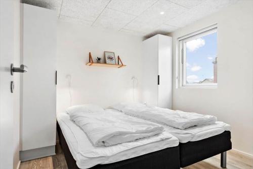 a bed in a room with white walls and a window at 941-Hvide-Sande-Langsand-167 in Hvide Sande