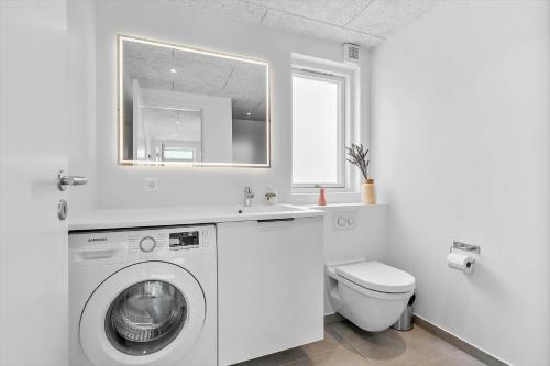 a white bathroom with a washing machine and a toilet at 941-Hvide-Sande-Langsand-167 in Hvide Sande