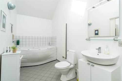 a white bathroom with a tub and a toilet and a sink at 706-Hvide-Sande-Slusen-6 in Hvide Sande