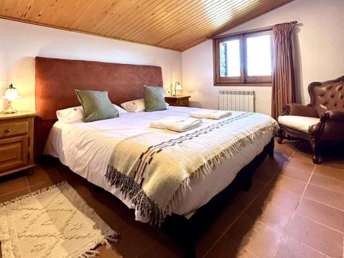 a bedroom with a large bed and a chair at Cal Grit casa de muntanya a Pont de Bar in Bar