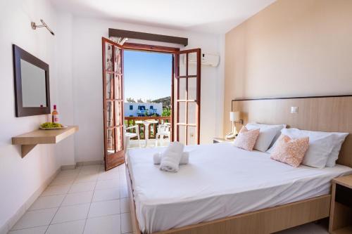 a bedroom with a large white bed and a balcony at Casa Garden in Karpathos