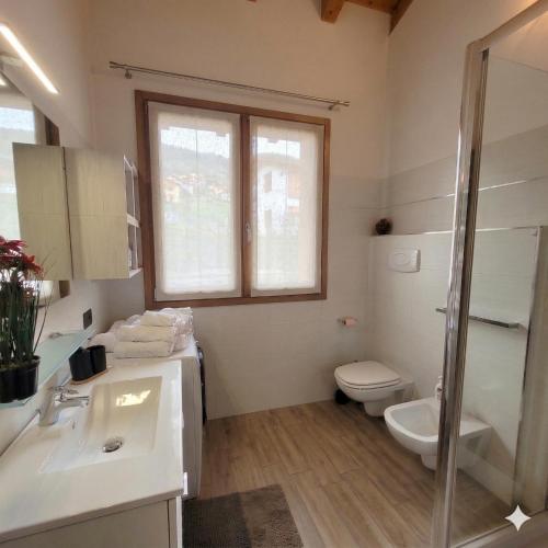a bathroom with a sink and a toilet and a window at Casa Gioia Alpina Mountain Lake Iseo Hospitality in Bossico