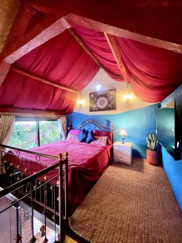 a bedroom with a red bed with a canopy at Backpackers Cabin with Mountain View in Bedugul