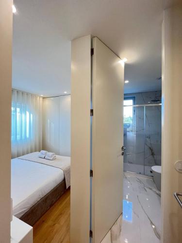 a bedroom with a bed and a bathroom with a shower at Brittos Home Lovely Stay - Villa Prime in Vila Nova de Famalicão