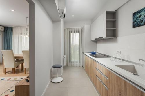 a white kitchen with a sink and a table at Athina Suites Hotel in Bucharest