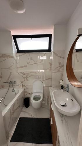 a white bathroom with a sink and a toilet and a tub at Warm apartament 3 in Bucharest