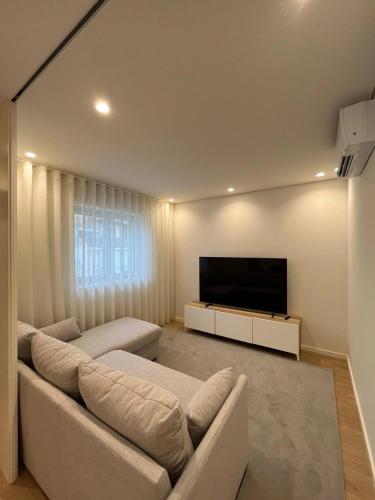 a living room with a couch and a flat screen tv at Brittos Home Lovely Stay - Villa Family in Vila Nova de Famalicão
