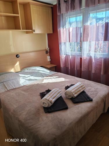 a bedroom with a bed with two towels on it at Mobil home au bord du lac de Foix in Foix