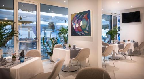 ノヴィグラード・イストラにあるRivalmare Boutique Hotelの白いテーブルと椅子、窓のあるレストラン